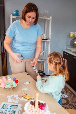 Küçük kız ve kadın manzarası bahar Paskalyası için şenlikli dekorasyonlar yapıyor. Anne ve kızı birlikte vakit geçiriyorlar. Dikey.
