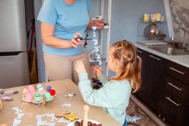 Küçük kız ve kadın manzarası bahar Paskalyası için şenlikli dekorasyonlar yapıyor. Anne ve kızı birlikte vakit geçiriyorlar..