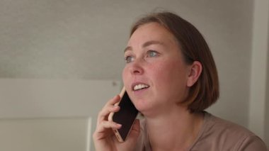 Kafkasyalı genç bir kadının portresi akıllı telefonuyla arıyor ve mutlu şaşkınlık ve şok duyguları yaşıyor. Psikoloji kavramı.