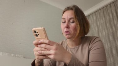 Akıllı telefon kullanan genç, beyaz bir kadının portresi. Heyecan hissi. Alt görünüm.