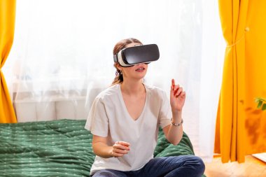 Kadın sanal mekanları keşfetmek için sanal gerçeklik kulaklığı kullanıyor, gelecekteki teknolojinin potansiyelini kucaklıyor. Orta çekim.