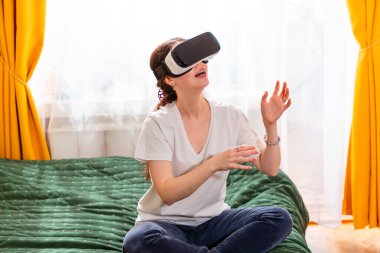 İç mekandaki kadın portresi, yenilikçi VR teknolojisiyle etkileşim içinde, hiper gerçekçi simülasyonlara adım atıyor, modern yapay zeka teknolojisi kavramı.