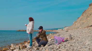 Gönüllüler kirliliği önlemek ve ekosistemi korumak için kıyı şeridi boyunca plastik atık topluyorlar. Çevre aktivistleri bir fren yapar ve çay içerler. Tam boy çekim.