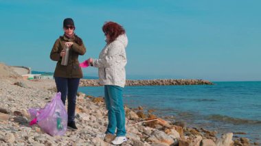 Çevre eylemcileri okyanus kıyısı boyunca plastik atık toplayarak kirliliği önlemeye ve kıyı şeridini onarmaya yardım ediyorlar. Gönüllüler Dünya Günü temizlik girişimine katılıyor. Boşluğu kopyala.