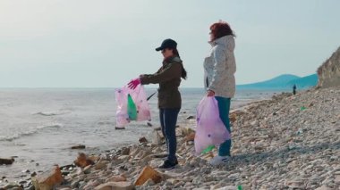Kadın çevreciler kıyı şeridindeki çöpleri temizleyip deniz hayvanlarını korumaya yardım ediyorlar. İnsanlar Dünya Günü için temizlik girişimine katılıyor. Tam boy çekim.