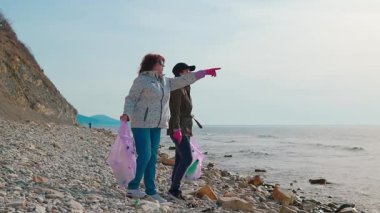 Gönüllüler, kirli bir plajdaki plastik atıkları temizlemek, çevresel yıkımı önlemek ve sorumlu atık imhasını desteklemek için çalışıyorlar. Tam boy çekim.