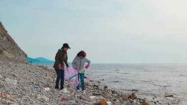 Gönüllüler, çevresel bir felaketi önlemek ve doğanın güzelliğini geri getirmek için kıyı boyunca plastik şişeler, torbalar ve diğer atıkları topluyorlar. Geniş açı.