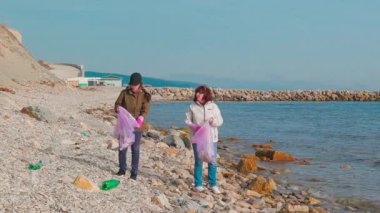 Kadın gönüllüler plajdaki plastik ve molozları temizliyor, çevresel hasarı önlüyor ve sorumlu atık imhasını destekliyor. Kirlilik ve deniz koruma kavramı. Geniş açı.