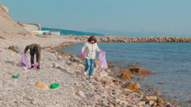Çevre gönüllüleri uzak bir sahilde okyanus kirliliğiyle savaşmak ve deniz yaşamını korumak için plastik atık ve diğer çöpleri topluyorlar. Ekolojik felaket ve doğa koruma kavramı. Geniş açı