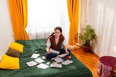Banka hesaplarını inceleyen ve bütçeyi optimize etmek için masrafları hesaplayan genç bir kadın. Mali istihbarat ve sorumlu ekonomi kavramı. Üst manzara, geniş açı.