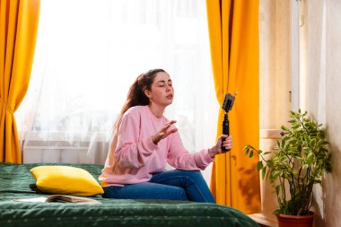 Genç iş kadını yatağında oturmuş, markalaşma ve pazarlama tavsiyelerini paylaşırken video çekiyor. Orta çekim.