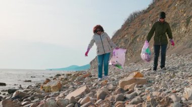 İki kadın plajdan çöp topluyor, plastik atıkları azaltıyor ve çevreyi koruyor. Gönüllüler okyanusu temizlemek ve deniz hayvanlarını kirlilikten korumak için harekete geçtiler..