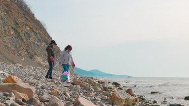 Çevreciler sahildeki atıkları temizlemek için birlikte çalışırlar. Gönüllüler kirliliğe karşı savaşmak ve deniz hayatını korumak için çalışıyorlar. Kadınlar fotoğraf çeker. Geniş açı. Boşluğu kopyala