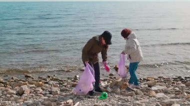Kadın eylemciler vahşi bir plajı temizlemek, plastik atık toplamak ve doğal çevreyi geri getirmek için diğer çöpleri toplamak için çalışıyorlar. İnsanlar Dünya Günü için bir koruma girişimine katılıyor. Boşluğu kopyala