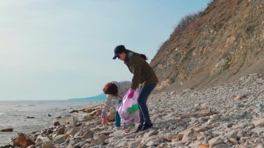 Gönüllüler, kirliliği azaltmak ve çevresel sorumluluk bilincini artırmak için plastik atık ve diğer çöpleri toplayarak vahşi bir kıyı şeridini yeniden inşa etmeye çalışıyorlar. Okyanus temizleme konsepti. Yan görünüm