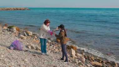 İki kadının deniz ekosistemini korumak için çöp topladığı sahil temizleme girişimi. Gönüllüler frene bassın. Kirlilik ve temizlik kavramı. Geniş açı
