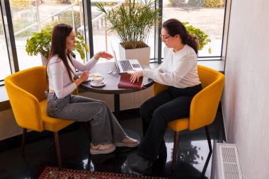 İki yaratıcı kadın öğle yemeği sırasında markalaşma tavsiyeleri veriyor. Yenilik ve takım çalışması kavramı. Yan görünüm.