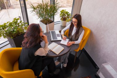 Güzel bir kafede, yaratıcı pazarlama ve proje geliştirme kavramında iki şık kadın arasında beyin fırtınası. Üst görünüm.