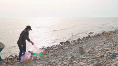 Eylemciler kirlenmiş bir kıyı şeridinden plastik atık toplayarak deniz yaşamını korumaya ve kirlenmeyi önlemeye yardım ediyorlar. Kopyalama alanı ile geniş çekim