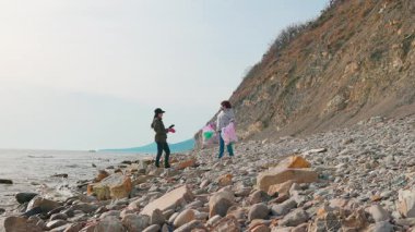 Eylemciler, deniz ekosistemlerini korumak ve doğal manzarayı geri getirmek için kirli bir sahilden çöp topluyorlar. Gönüllüler fotoğraf raporu alır. Geniş açı