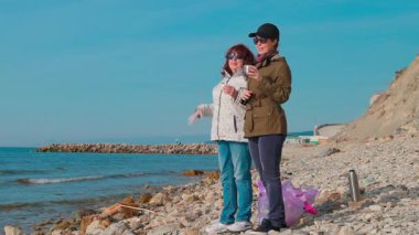 Gönüllüler, okyanus kirliliğini önlemek ve vahşi yaşamı korumak için kıyı şeridi boyunca plastik ve diğer atıkları topluyorlar. Kadınlar bir fren yapar ve çay içerler. Tam boy çekim