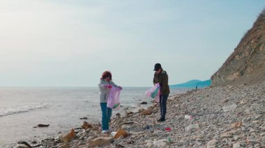 Çevreciler, okyanus kirliliğini önlemek ve doğayı korumak için sahilden çöp topluyor. İnsanlar Dünya Günü 'nde çevreyi yeniden düzenleme girişimine katılıyorlar. Geniş açı
