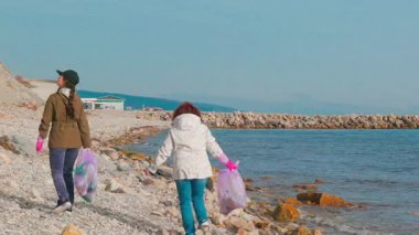 Kadın gönüllüler çevresel hasarı önlemek ve okyanusun korunmasının önemi hakkında farkındalığı artırmak için kumdan çöp topluyor. İnsanlar doğayı plastikten temizlemek için harekete geçerler..