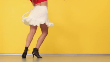 Kadın, çeviklik ifadesini ve spor motivasyonunu vurgulayarak profesyonel çalışma alanında zorlu dans rutininden geçiyor. Ayakları sarı arkaplanda kapat. Tango dansı.