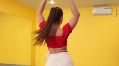 Odaklanmış beyaz kadın dansçı beden eğitimi dersinde rutin antrenman yapıyor. Güç zarafeti ve disiplinli spor tekniklerini ön plana çıkarıyor..