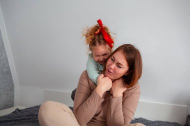 Genç anne ve kızının birlikte oynadığı ve kanepede otururken eğlendiği bir fotoğraf. Anneler Günü kavramı.