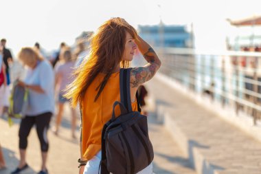 Sırt çantası takan ve sokakta yürüyen dövmeli genç bir kadın. Özgürlük ve yaz tatili.