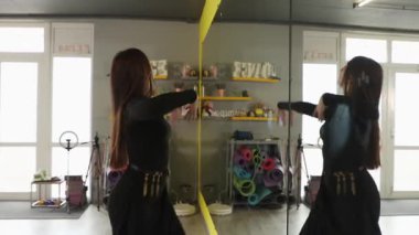 Beyaz kadın güçlü vücut dinamik eğitimi ve pozitif spor zihniyetini yansıtan aynanın yakınındaki fitness stüdyosunda koreografik tatbikat yapıyor. Yan görünüm.