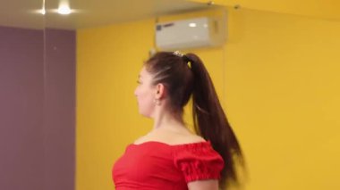 Antrenmandaki beyaz kadın parlak spor salonunda yoğun dans performansı sergiliyor. Güç hareketi atletik özveriyi ve vücut pozitifliğini yansıtıyor. Arkadan bak. Salsa dansı.