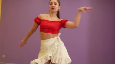 Coşkulu beyaz kız fitness kulübünde spor eğitimi sırasında odak ve zarafetle dans ederek esneklik disiplini ve sağlıklı vücut kültürünü ön plana çıkarıyor. Orta çekim.