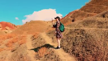 Birkaç arkadaş açık mavi gökyüzü altında engebeli çöl arazisinde yürüyüş yapıyor, rehberli eko-turizm gezisine katılıyor ve vahşi doğada seyahat özgürlüğünün tadını çıkarıyorlar. Geniş açı