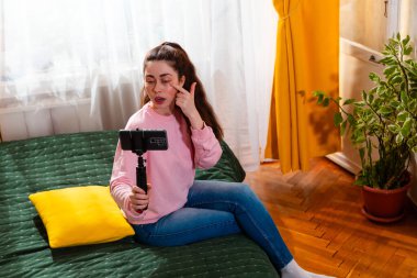 Sosyal medya stratejisti bir yatakta oturup izleyicileri için anlayışlı bir video çekiyor. Genç Kafkas kadın blog yazarı.