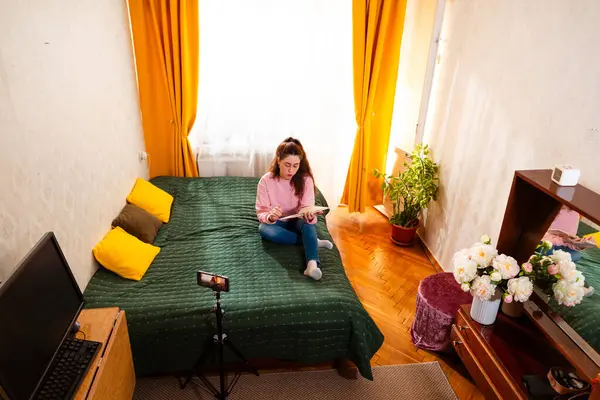 Yaratıcı bir kadın, dijital izleyicisiyle online iş stratejilerini paylaşırken bir video bloğu çekiyor. Geniş açı, üst görünüm.