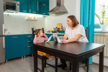 Gülümseyen kadın mutfak ortamında yeni yürümeye başlayan kızla oynuyor. Ev ortamında Montessori öğrenimi, aile bağı ve çocuk psikolojisi kavramı. Orta çekim.