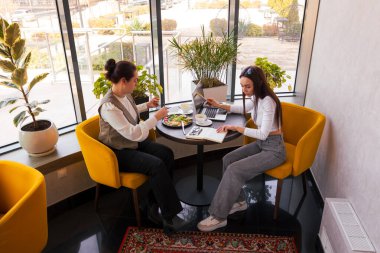 Girişimciler öğle yemeği yerken proje uygulamasını tartışıyorlar. Uzaktan çalışma, liderlik ve iş berraklığı kavramı. Üst manzara, geniş açı.