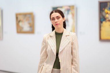 Sanat galerisinde tefekkür eden zarif ceketli beyaz bir kadının portresi. Kültür Eğitimi ve Müze Günü kavramı.