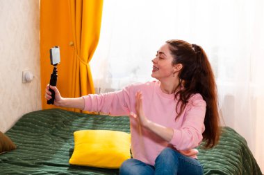 Şık bir girişimcinin portresi samimi bir yatakta oturmuş iş başarısını tartışırken ilgi çekici bir video kaydediyor. Mutlu genç kadın blogcu olarak.