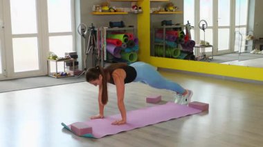 Kararlı esmer, vücudunu çekirdek güçlendirici bir pozisyona sokuyor. Temiz stüdyo ve doğal ışık motivasyon ve refah ortamı yaratır. Geniş açı.