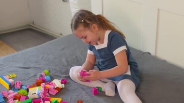 Beyaz çocuk, evde öğrenim alanında çok renkli bloklarla oynamaktan hoşlanıyor. Hayal gücü ve pratik eğitim kavramı. Orta çekim.