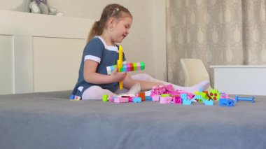 Anaokulu öğrencisi yatağın üzerinde küplerle çeşitli şekiller yapar. Bağımsız oyun erken gelişimi ve odaklanmayı geliştirir. Düşük açı görünümü.