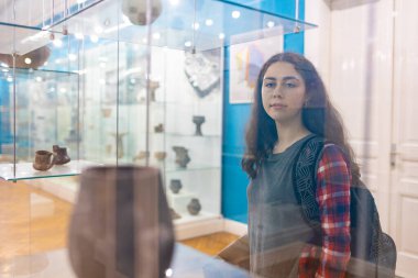 Cam galeride arkeolojik çömlek sergisini izleyen kadın ziyaretçi, Uluslararası Müze Günü 'nde eğitim ve tarihi kutluyor.