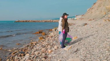 Gönüllüler sahilin doğal güzelliğini geri getirmek ve deniz hayvanlarını plastik atıklardan korumak için uzak bir kıyı şeridindeki çöpleri çıkarıyorlar. Çevre temizliği ve korunma çabası. Geniş açı..