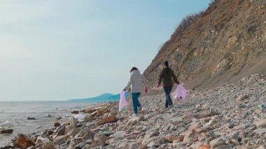  Gönüllüler, okyanus kirliliğini önlemek ve doğayı korumak için sahil boyunca plastik atık ve diğer çöpleri topluyorlar. İnsanlar Dünya Günü koruma çabalarının bir parçası olarak çevreyi temizliyor. Geniş açı.