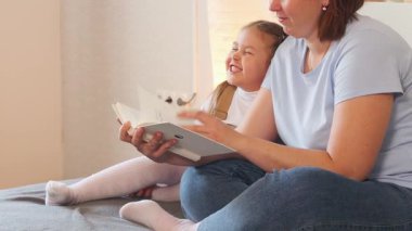 Bir anaokulu kızı ve annesi bir yatakta birlikte masal okudular. Erken okuma becerileri ve ev bazlı gelişim. Kapat..