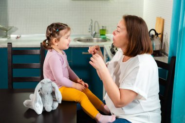 Sıcak bir mutfak ortamında anne ve genç kız arasında eğlenceli bir öğretim. Öğrenme, gülme ve sevgi dolu ilgi kavramı. Yan görünüm.