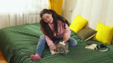 Gayri resmi kıyafetli güzel esmer, tavşan kürkünü dikkatlice tarıyor, evcil bakım ve hayvan bakımı kavramını. Geniş açı.